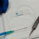 A syringe is used to pump liquid through the microfluidic channels.  It's unsuccessful, and the liquid breaks the metal-silicone seal.